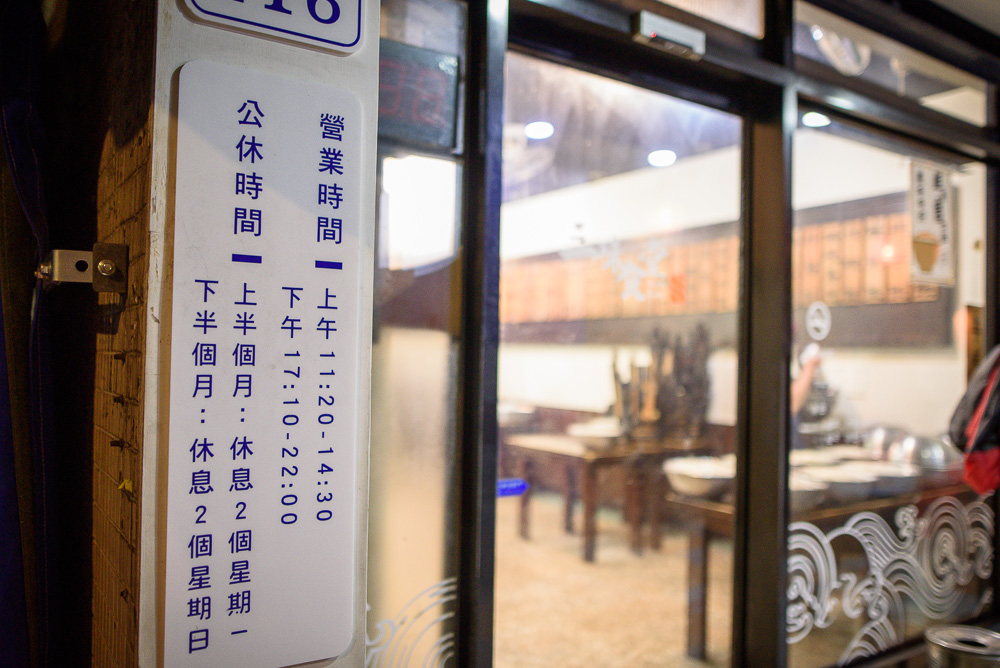 台北三味食堂｜餐廳門口，張貼營業時間與公休日告示的白色招牌。