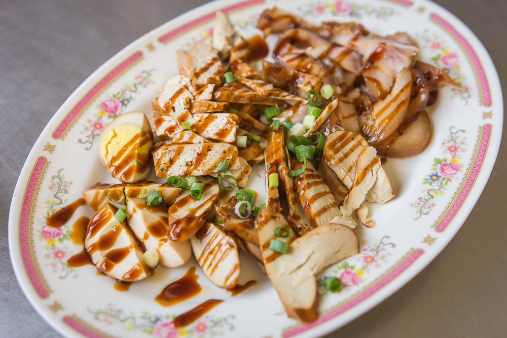 苗栗外省牛肉麵|牛肉麵配酸菜與辣椒油,滷豆干、豬耳朵切盤可當小菜 7 苗栗外省牛肉麵|盤中盛裝滷蛋、豆乾與滷味切片,置於金屬桌面。