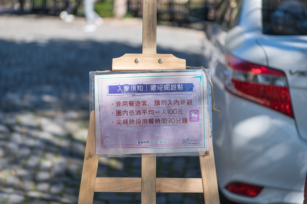 南投蒙塔妮甜點｜木製畫架，告示牌，戶外停車場，白色轎車。