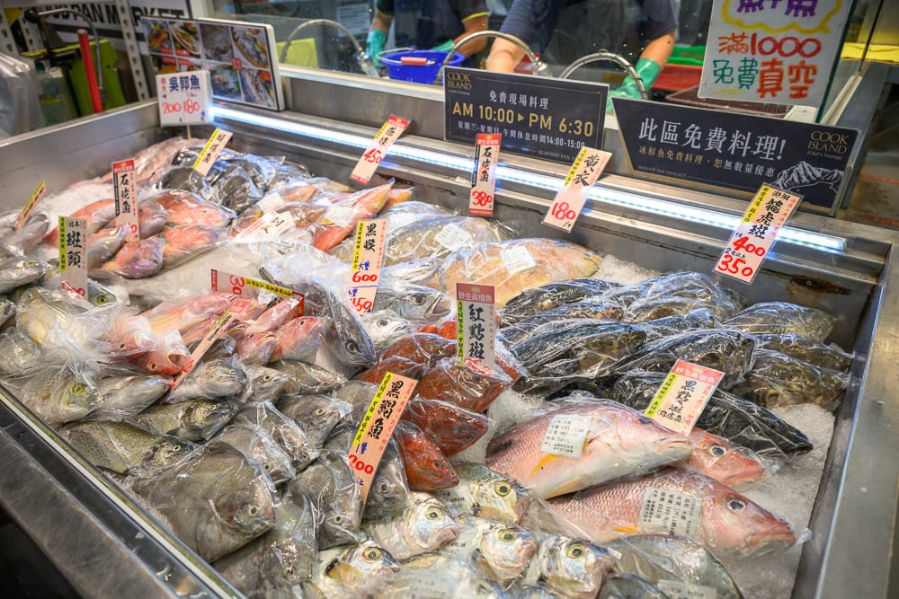 台中阿布潘水產｜超市生鮮冷藏櫃，料理，各式鮮魚，冰塊，價格標籤，透明塑膠袋，中文招牌，不鏽鋼檯面。