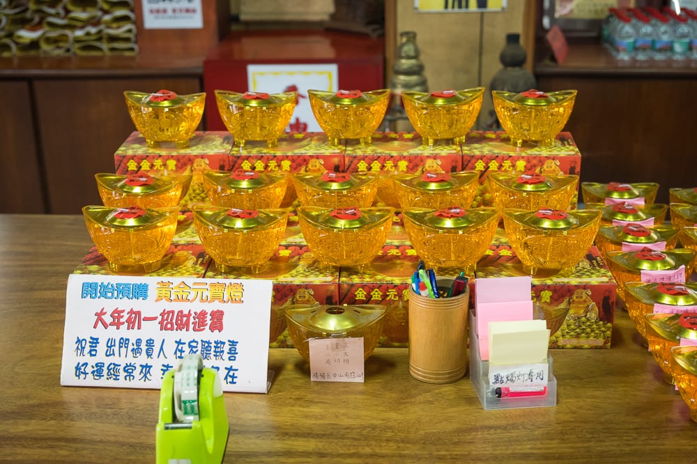 桃園白蛇廟｜室內木桌，金元寶造型燈，紅底黃字告示牌，筆筒，便利貼架，膠帶台，紙箱。