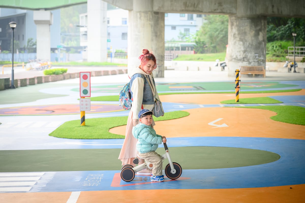 苗栗滑步車公園｜高架橋下廣場，紅髮女子，男童，三輪車，迷你紅綠燈，彩繪跑道，水泥柱，背心。