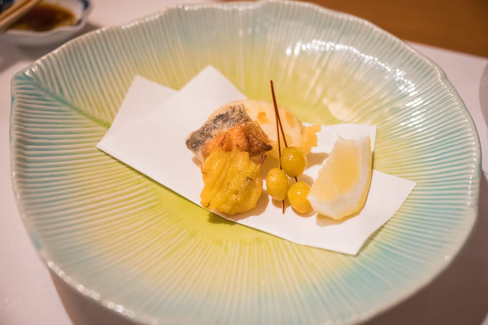 日本白老星野界波羅多｜料理,淺綠色葉脈造型瓷盤,炸魚肉,銀杏串,檸檬塊,白色吸油紙。深淺綠色交錯的寬口圓盤內，擺放炸物與柑橘切片，旁邊有醬汁碟。